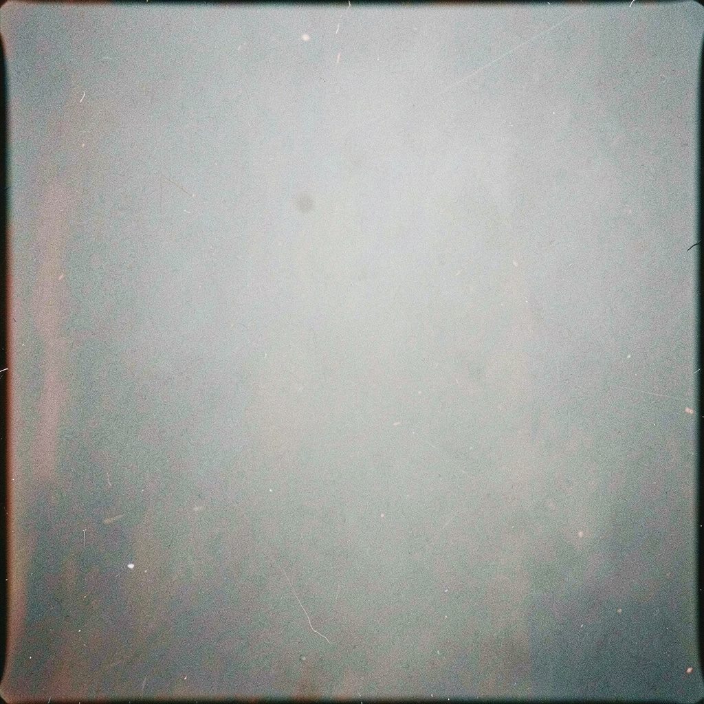 A grainy analog photograph of a stack of paper documents and a pen on a wooden desk, muted brown and grey tones, quiet administrative mood